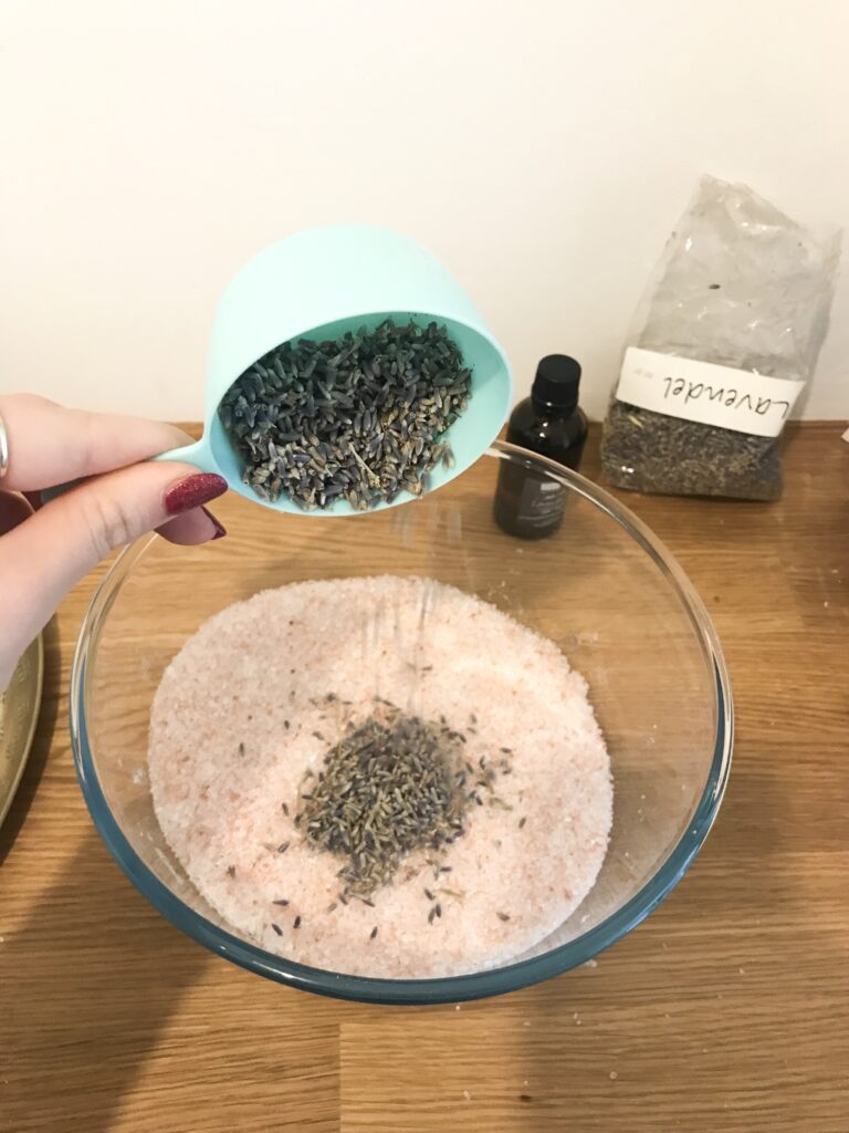 Pouring dried Lavender into bowl of salts