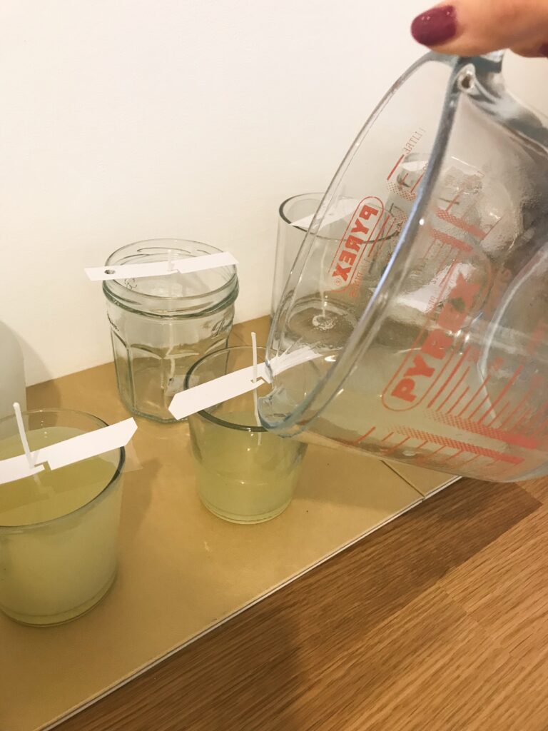 Pouring scented soy wax into jars for candle making