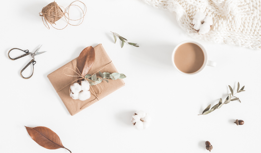 Brown paper gifts wrapped on a white desk, with tea and white flowers
