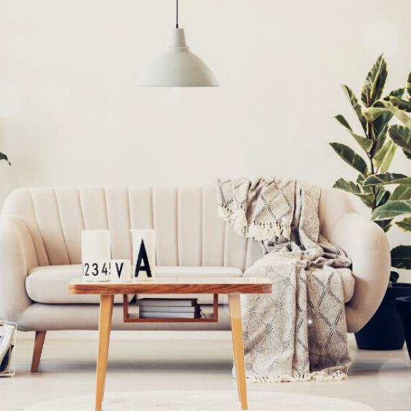 Scandinavian style lounge with sofa, blanket, coffee table and lots of plants.