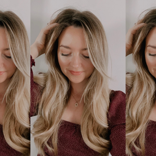 Rosie, with loose curls, in a dark red top looking down and smiling