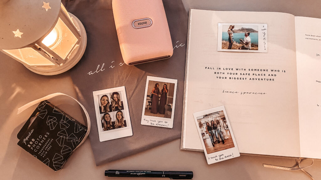 Table with pink Instax Mini Link, printed photos and wedding journal