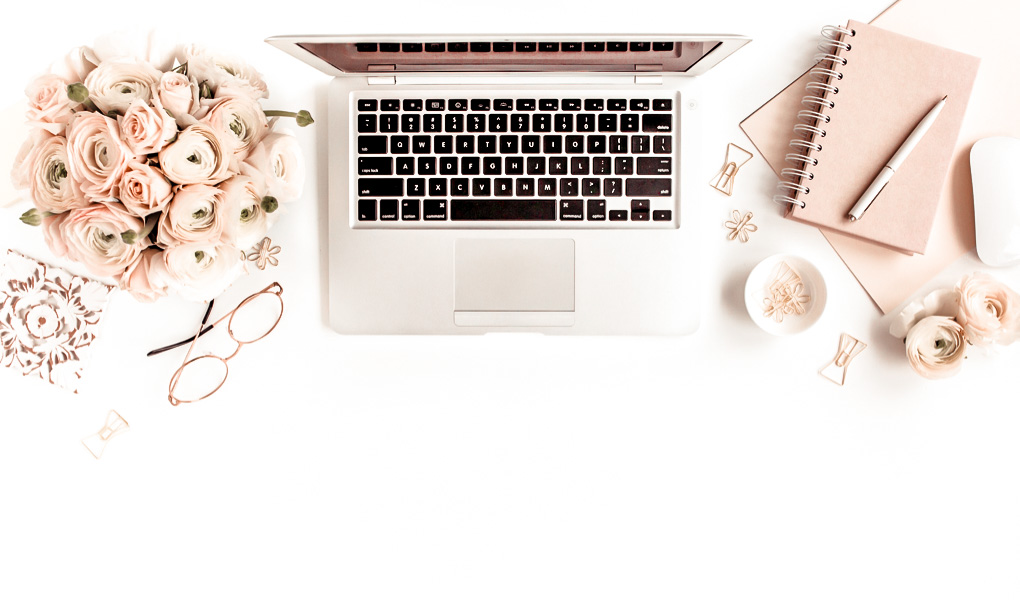Desk with flowers, apple laptop and pink notebook