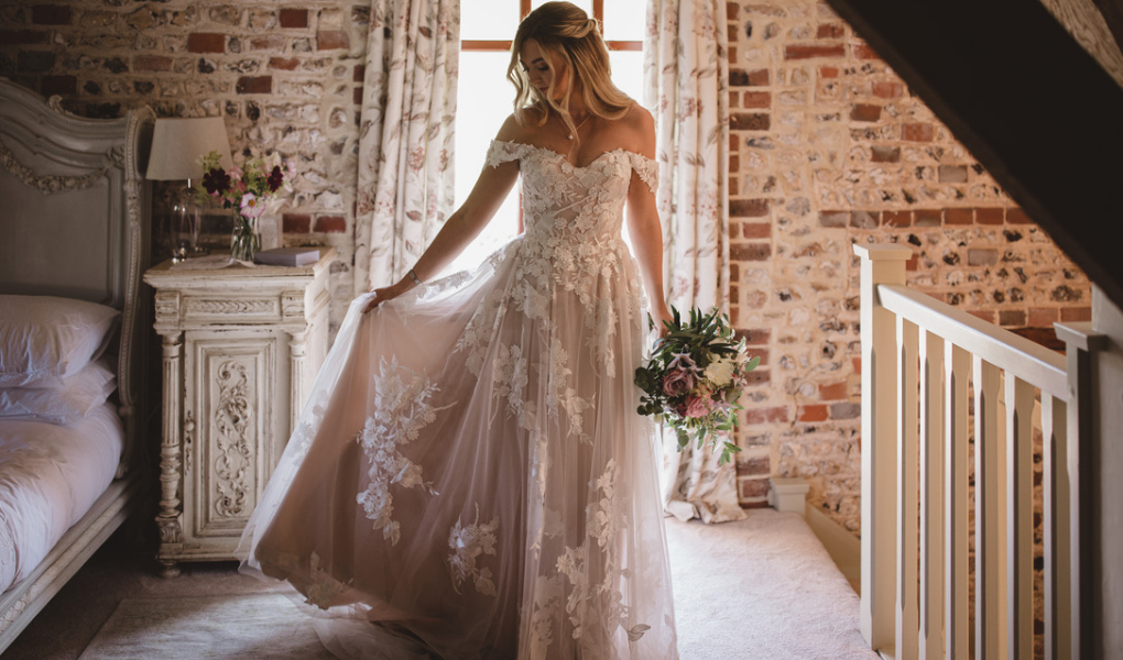 Rosie in english cottage wearing her Madi Lane bridal gown and holding her bridal bouquet.