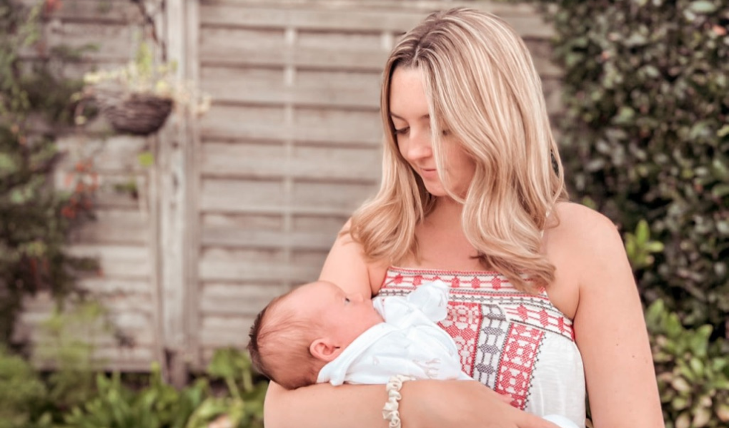 Rosie holding baby Winnie in her arms, whilst standing in the garden on a summers day.